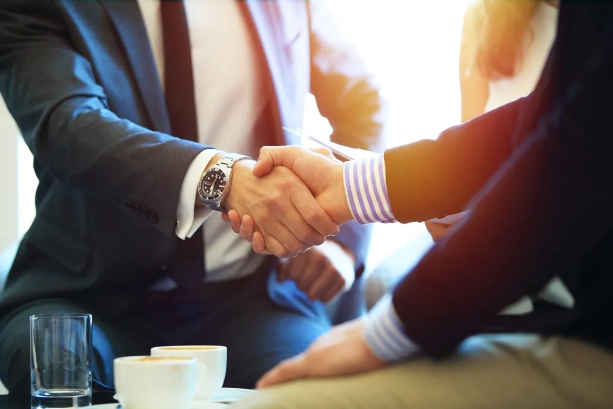 Two people shaking hands across a table