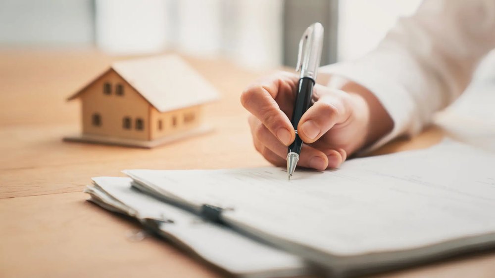 Signing mortgage paperwork beside a model house